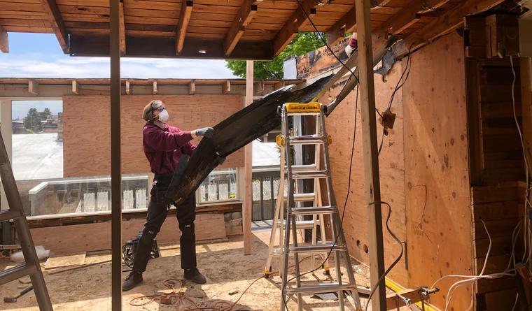 Worker removing a damaged beam during a home rebuild
